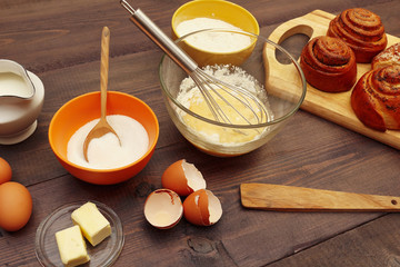 Cooking pastries from ingredients to fresh buns on a wooden table.