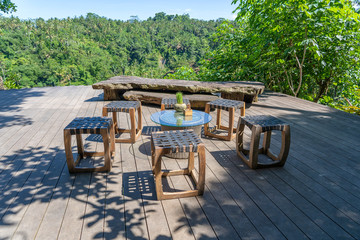 Wooden table and chairs in empty tropical cafe next to rice terraces in island Bali, Indonesia