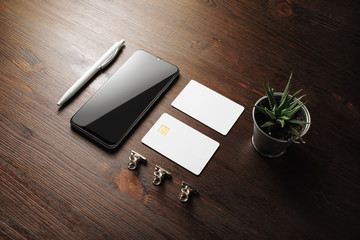 Blank branding mockup. Smartphone, business card, credit card, plant and pen on wooden background.