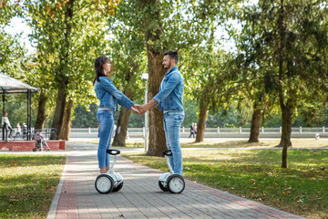 A young couple riding a hoverboard in a park, self-balancing scooter. Active lifestyle technology future