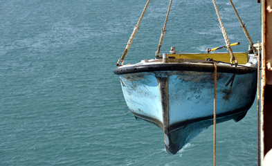 Suez Canal crew boat hanging on the side of the canal transiting vessel. 