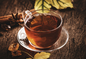 Autumn hot black tea in glass cup, old wooden table background, selective focus