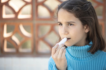 Niña aplicando protector labial en el exterior