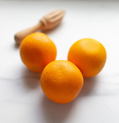 oranges and hand citrus squeezer on a marble background with copy space