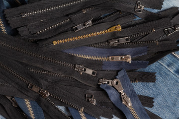 Fototapeta na wymiar Pack a lot of black navy metal brass antique zippers stripes with sliders pattern for handmade sewing tailoring leathercraft on the blue wooden background