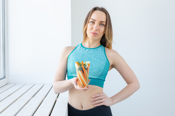 Diet concept - Healthy lifestyle woman holding vegetables indoors. Young female eating healthy food.