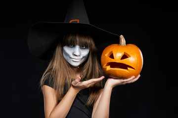 Halloween witch girl showing Jack-O-Lantern pumpkin on palm