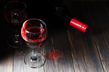 Red wine in glasses. Bottle of wine. Dark brown wooden background. Copy space