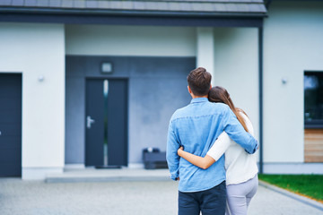 Couple in front of one-family house in modern residential area - obrazy, fototapety, plakaty