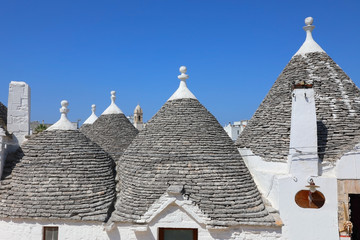 Fototapeta na wymiar The conical roofs of a white Trulli houses. Apulia, Italy