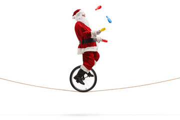 Santa claus riding a unicycle on a rope and juggling