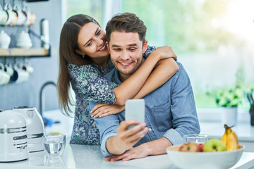 Couple in home kitchen using smartphone