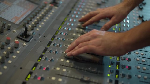 Close-up of a mixing console, the hand adjusts the faders. Sound director works in the studio. Professional recording studio. Recording Concept.