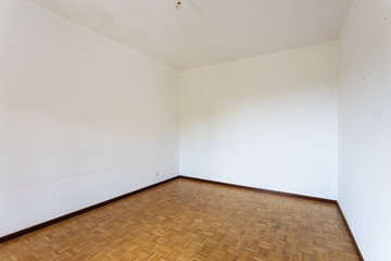 Empty room with all white walls and parquet floor