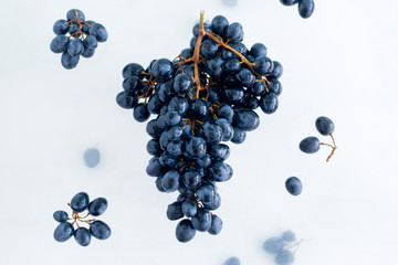 fresh ripe organic black grapes levitate in the air on white background, healthy eating and lifestyle