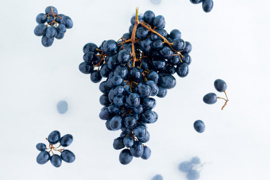 fresh ripe organic black grapes levitate in the air on white background, healthy eating and lifestyle © dvulikaia