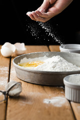 Front view of hand pouring flour in tray