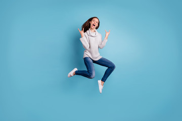 Fototapeta na wymiar Full length photo of cheerful content youth jump show horns signs jump feel rejoice have weekend party wear white pullover denim jeans sneakers isolated over blue color background