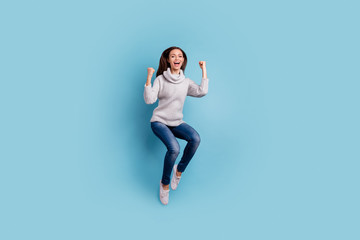 Fototapeta na wymiar Full length photo of cute enthusiastic lady jump raise fists scream yeah celebrate victory wear white pullover sweater denim jeans sneakers isolated over blue color background