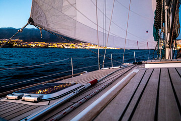 Concept of sailing with. sail boat in excursion trip for holiday vacation - ocean and coastline in background