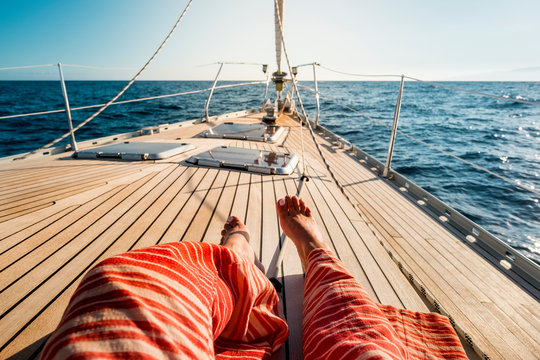 Close up of tourist woman caucasian feet lay down and relaxing enjoying a sail boat trip with ocean around and horizon in background - concept of luxury happy vacation for people