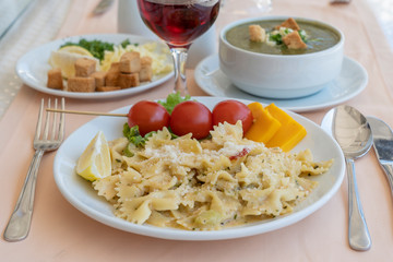 Pasta farfalle with cherry tomato and cheese in white plate, closeup