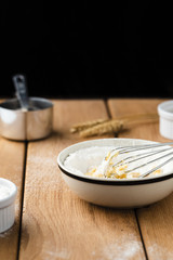 Front view of bowl and whisk on wooden table