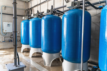 Drinking water factory or plant production, industrial interior. Large metal tanks for filtering and potable water treatment from well