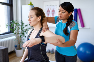 Chinese woman physiotherapy professional giving a treatment to an attractive blond client in a bright medical office