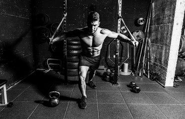 Fototapeta na wymiar Young strong focused fit muscular man chest bench press stretching workout training in the gym with rubber for strength and good looking of muscles dark image real people training selective focus