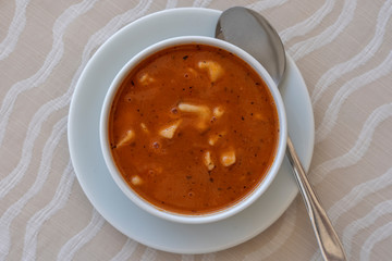 Red tomato soup with dumplings in a white bowl, close up