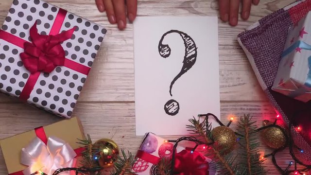 White sheet with text. Question mark. Presents for the family. Beautiful presents under the Christmas tree. New Year interior. Happy holidays. New Year's gift box. Holidays and celebrations concept