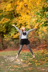 Beautiful little girl with autumn leaves in the park