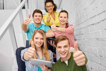 education, technology and learning concept - group of happy international high school students or classmates with tablet pc computers sitting on stairs