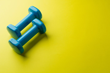 Two blue dumbbells for the girl on a yellow background