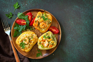 Vegetarian dish. Peppers stuffed with quinoa, shrimp  and vegetables on dark stone table. Top view flat lay. Free space for your text.