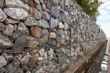 Stone walls for blocking the collapsing stone. Stone background. Stone wall covered with a net. stone gabion wall.