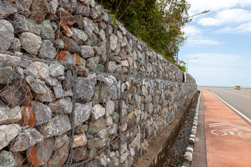 Stone walls for blocking the collapsing stone. Stone background. Stone wall covered with a net. stone gabion wall.