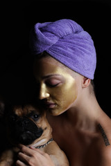 Portrait girl with golden mask and french bulldog, black background