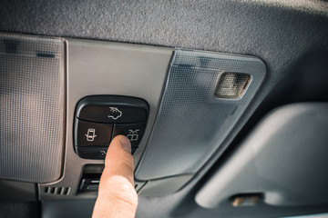 A man turns on the backlight button on the ceiling of a car to read