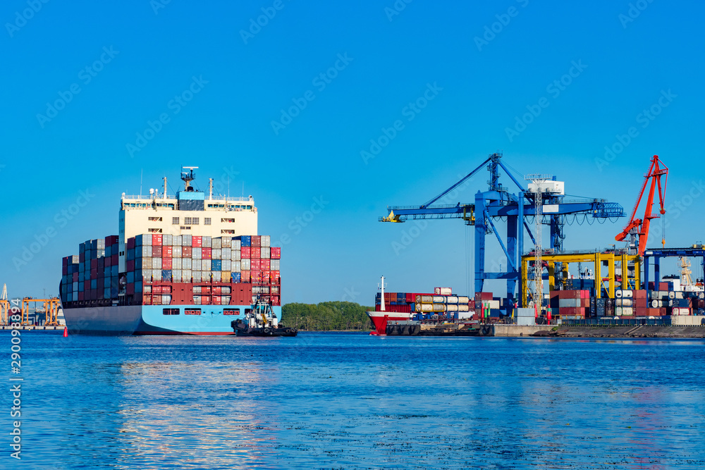 Poster the merchant ship is loaded with colorful containers. the work of the commercial sea port. cranes in