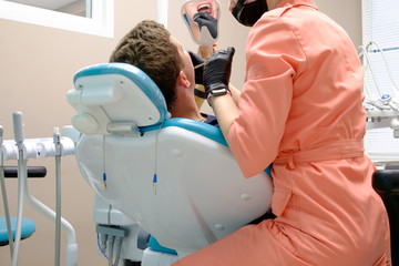 Girl dentist examines a patient in a chair