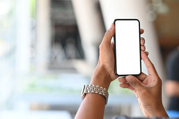 Smartphone on man's hands with empty screen and bokeh on blur room background.
