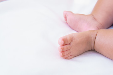 asian baby's feet are sleeping on a white bed sheet with copy space
