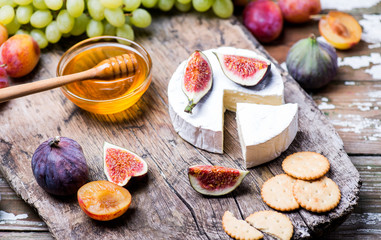 Dinner set with honey, cheese and fruits on a wood.