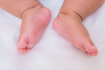 asian baby's feet are sleeping on a white bed sheet with copy space