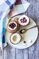 Berry dessert with yogurt in a cup of coconut on a wooden background. Blackberries, raspberries, blueberries, black currants. Blue napkin
