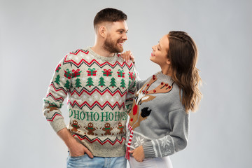 christmas, people and holidays concept - portrait of happy couple at ugly sweater party