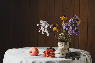 Still life with old flowers, apples, clusters of mountain ash
