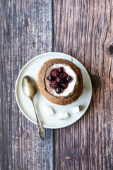 Berry dessert with yogurt in a cup of coconut on a wooden background. Blackberries, raspberries, blueberries, black currants.